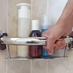 A hand using the PLUS Series Corner Shelf in Chrome Polished Finish as a grab bar for support.